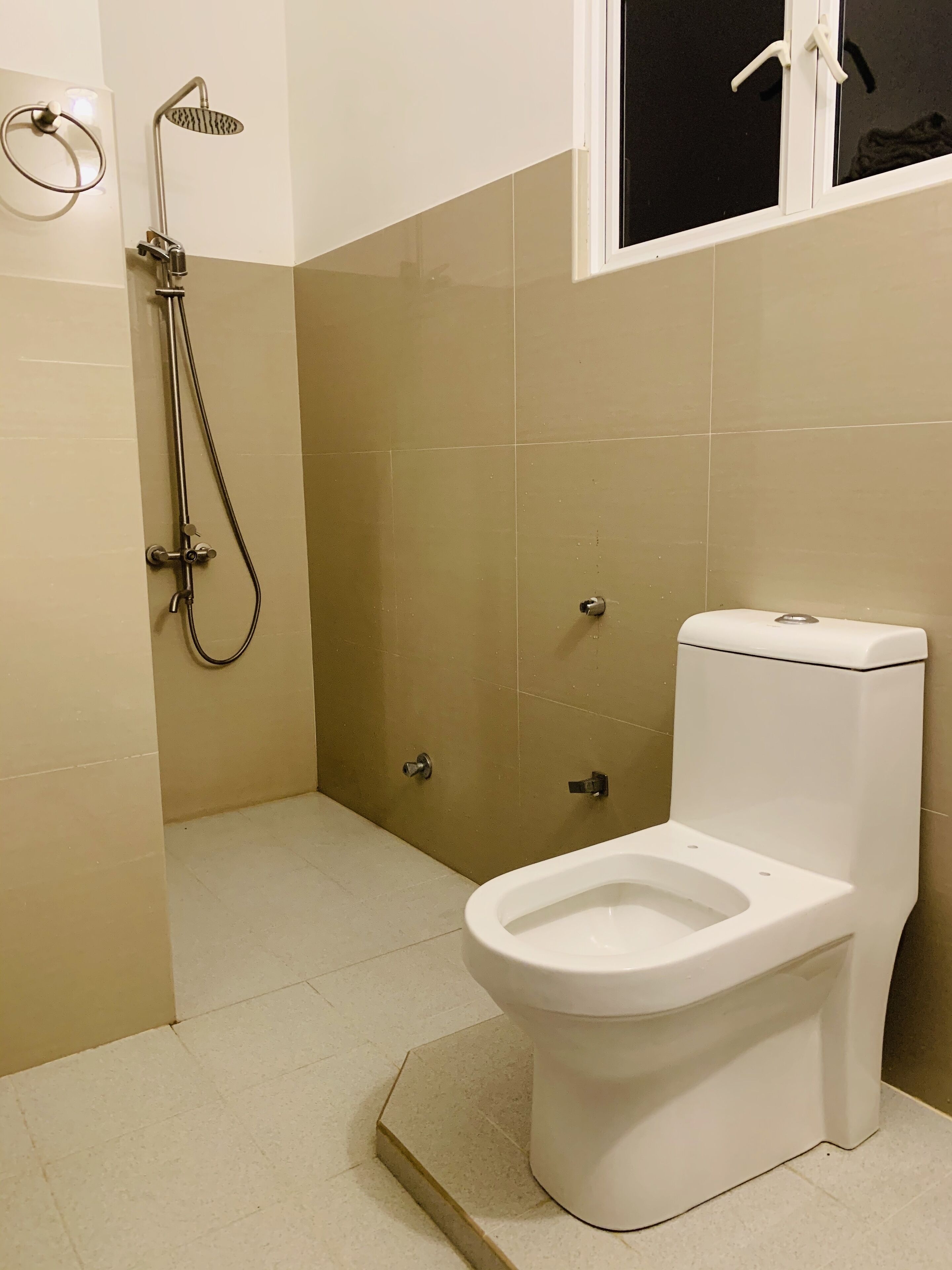 A bathroom with a toilet, a shower, and a window.