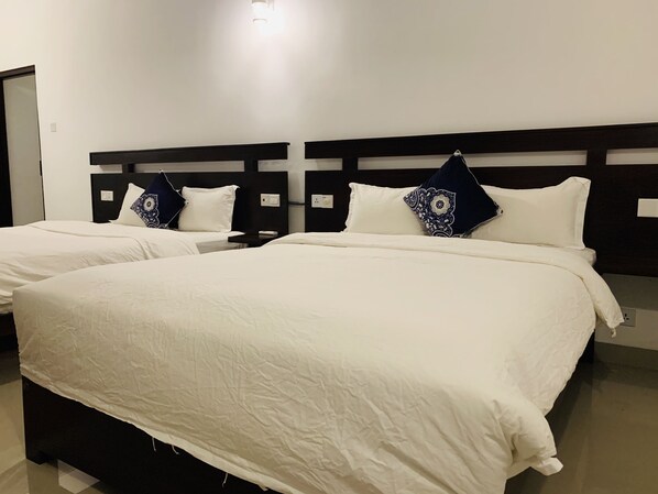 Une chambre d’hôtel avec deux lits, chacun étant équipé de draps blancs et d’oreillers à motifs.