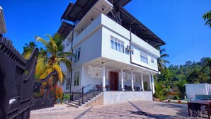 A two-story building with a covered porch and a staircase leading to the entrance. - Lavenro Hotel & Resort (Deniyaya)