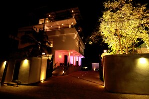 A multi-story building with a well-lit entrance and a staircase leading to the upper levels.
