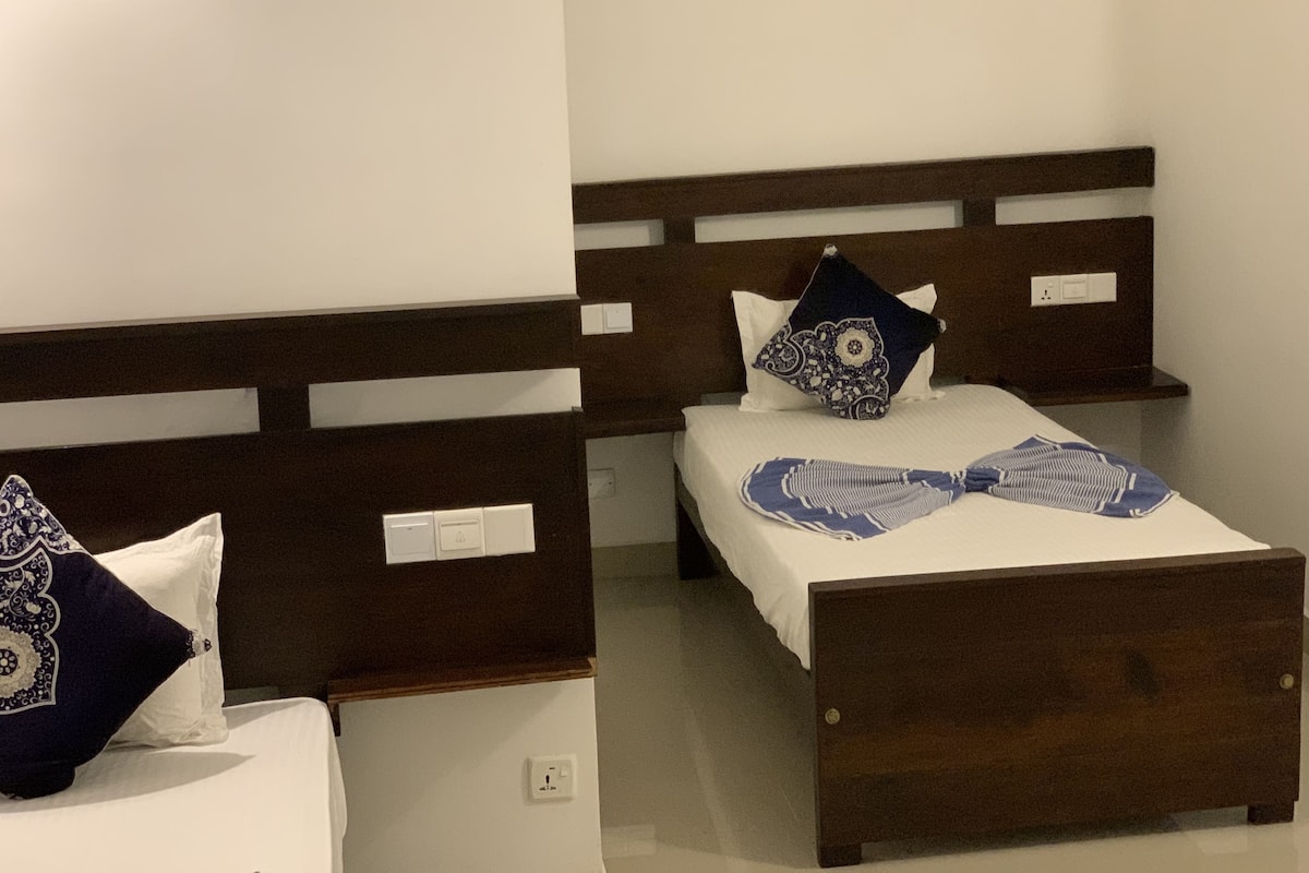 Une chambre d’hôtel avec deux lits, chacun doté d’une tête de lit en bois, de draps blancs et d’oreillers décoratifs.
