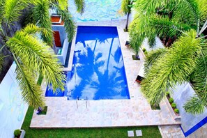 A rectangular pool with a blue water surface, surrounded by a stone deck and palm trees. - Villa 171 bentota (Aluthgama)
