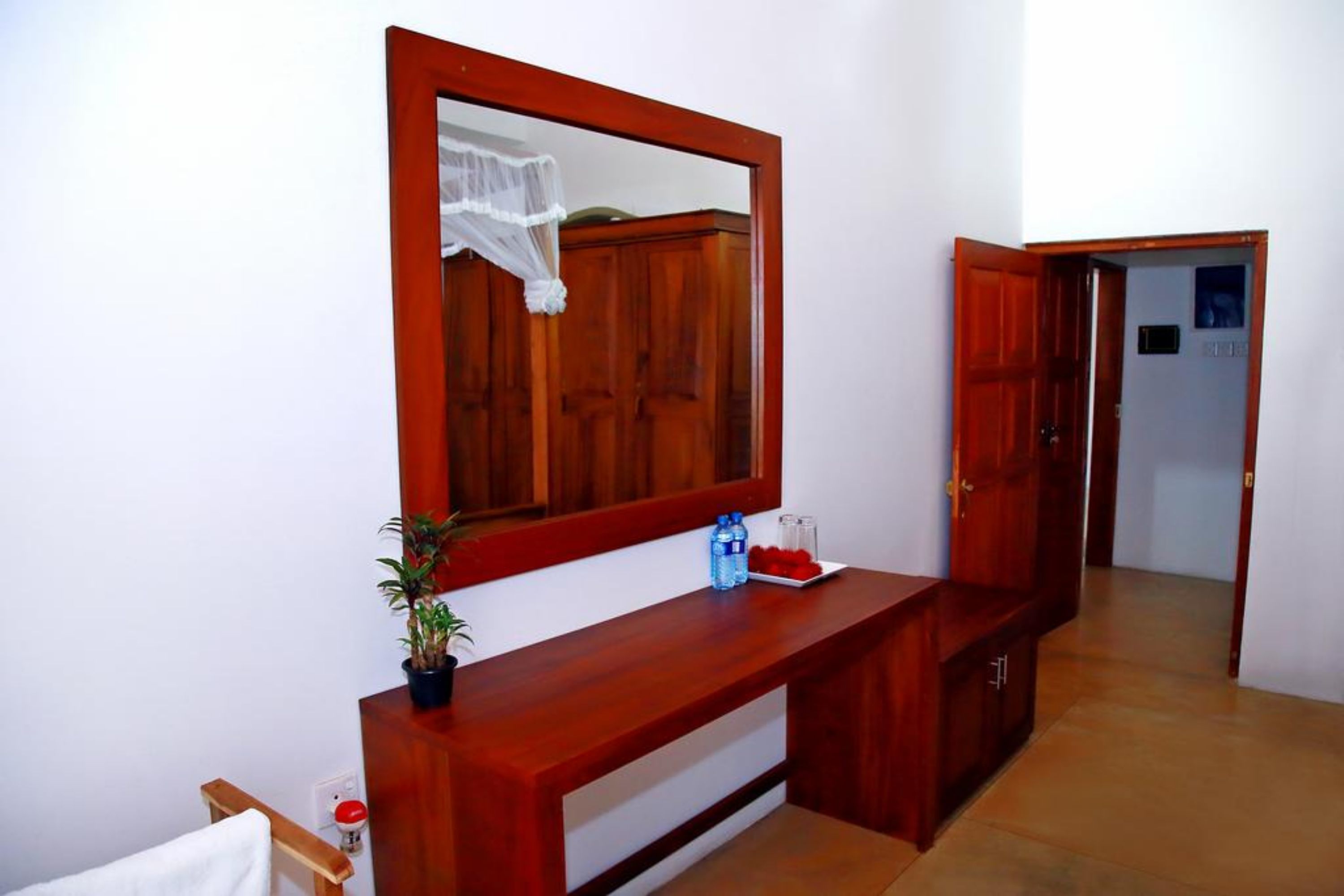 A wooden console table with a mirror, a potted plant, and a tray with fruit.
