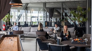A modern lounge area with sofas, tables, and a shuffleboard table. - Arenahotellet i Uppsala (Uppsala)