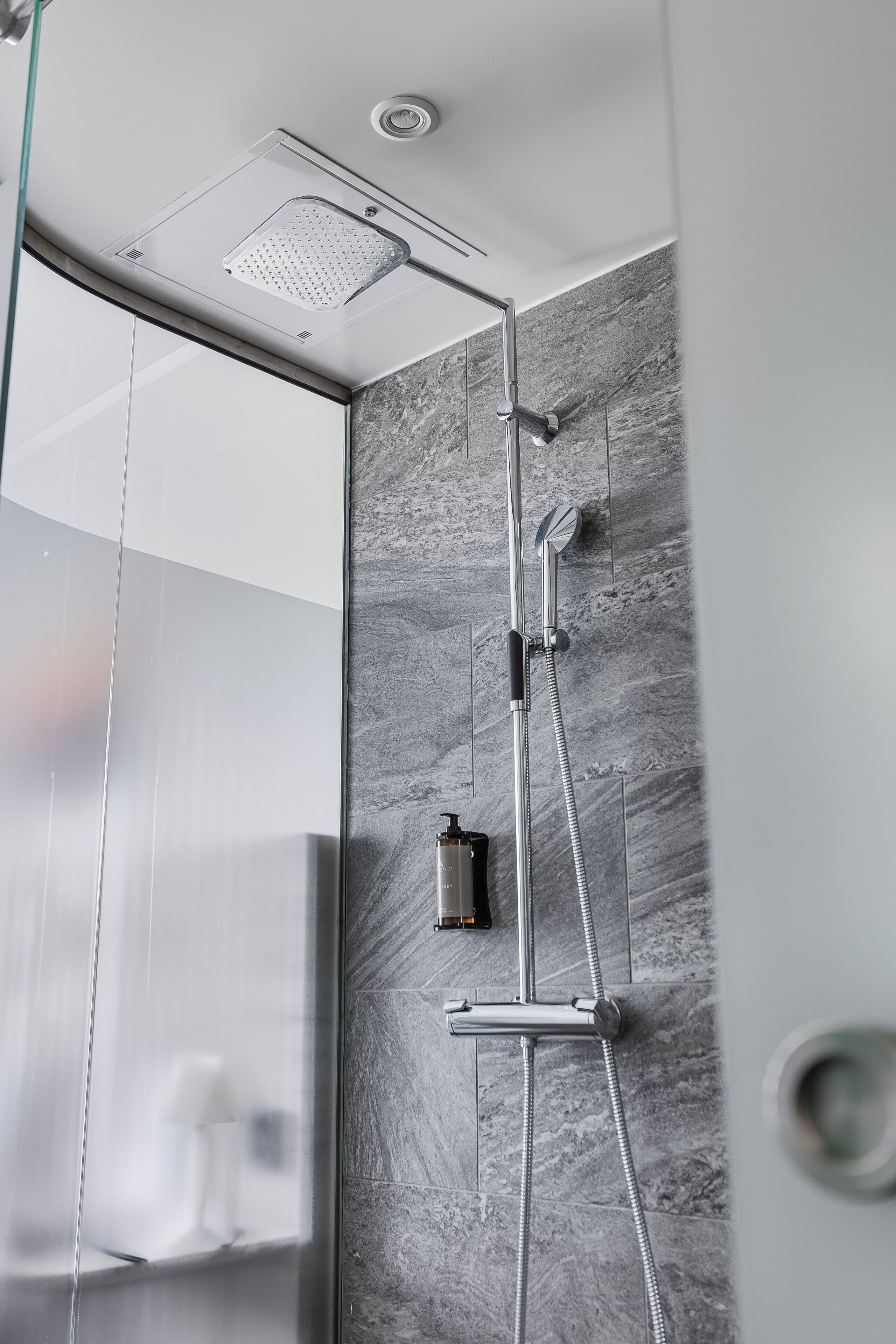 A modern shower with a handheld showerhead and a wall-mounted faucet.