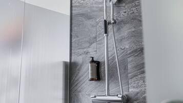 A modern shower with a handheld showerhead and a wall-mounted faucet.