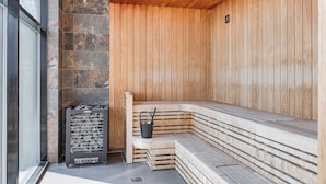 A sauna with wooden benches and a stone wall. - Arenahotellet i Uppsala (Uppsala)