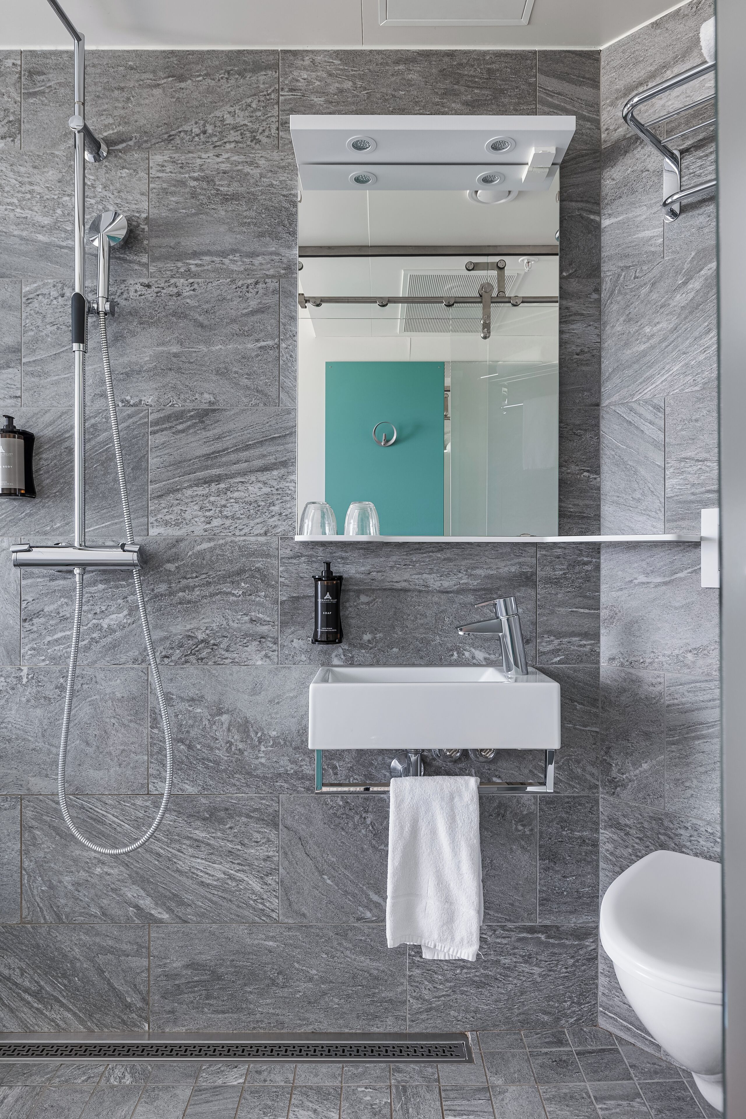 A modern bathroom with a shower, sink, and toilet.