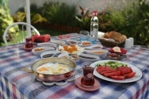 A table with various dishes, including a plate of sliced tomatoes and a bowl of eggs. - Degirmenli Konak (Cesme)