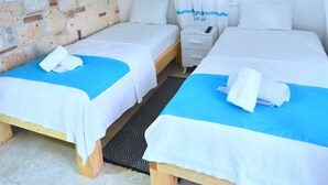 A room with two beds, a stone wall, an air conditioning unit, and a hanging light fixture. - Degirmenli Konak (Cesme)