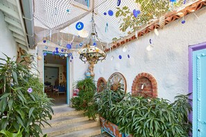 A staircase with steps leading up to a door, surrounded by potted plants and a hanging net with decorative items. - Degirmenli Konak (Cesme)