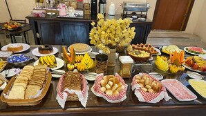 A buffet with various food items including bread, pastries, fruits, and desserts. - Pousada Sítio Sossego (Petrópolis)
