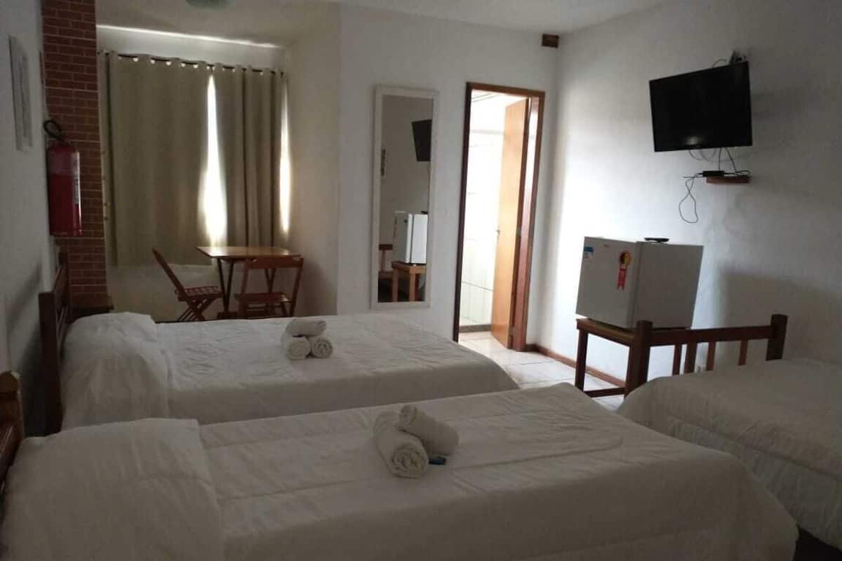 A hotel room with two beds, a TV, a desk, and a chair.