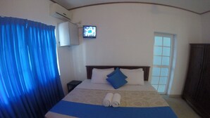 A hotel room with a bed, a TV mounted on the wall, a window, and a wardrobe. - Tripper's Private Villa (Negombo)