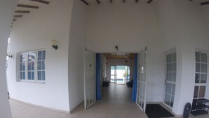A spacious indoor area with a tiled floor, a central open space, and a view into another room through a glass door. - Tripper's Private Villa (Negombo)