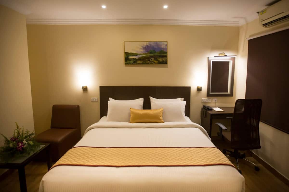 Habitación de hotel con una cama grande, un escritorio, una silla y un cuadro en la pared.