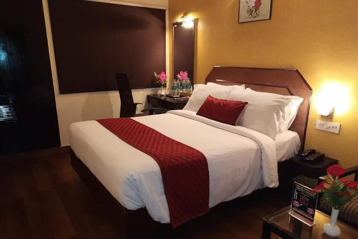 Una habitación de hotel con una cama grande, mesita de noche y una lámpara fijada a la pared.