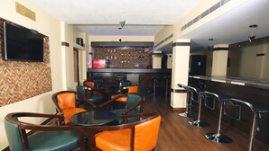 A bar area with wooden flooring, bar stools, and a flat-screen TV mounted on the wall. - Hotel Ashok Residency (Chennai)