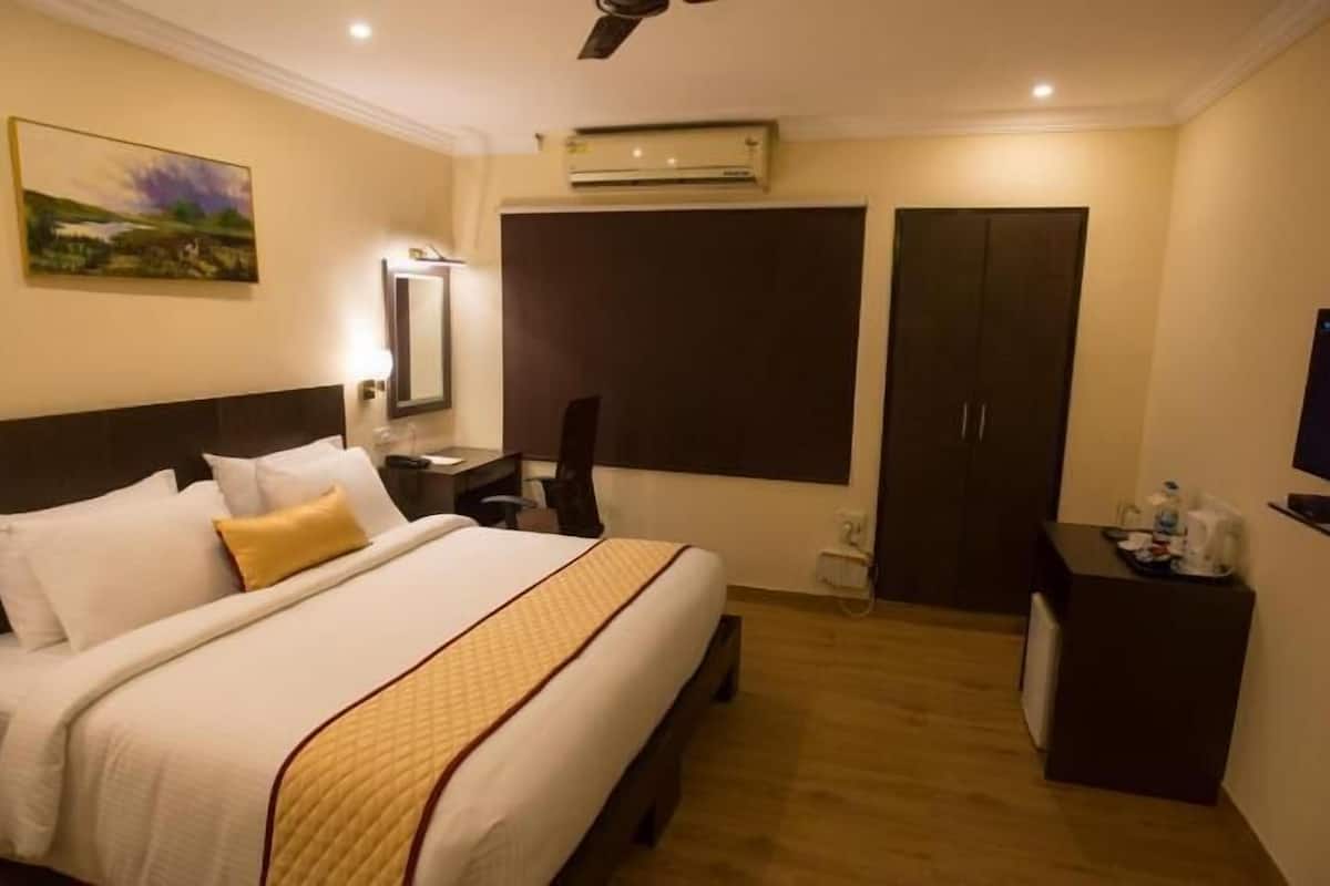 Una habitación de hotel con cama, escritorio, silla, televisión y armario.