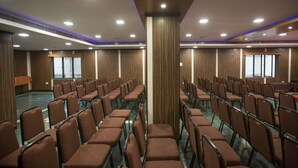 A conference room with rows of brown chairs, a podium, and a large pillar. - Hotel Ashok Residency (Chennai)