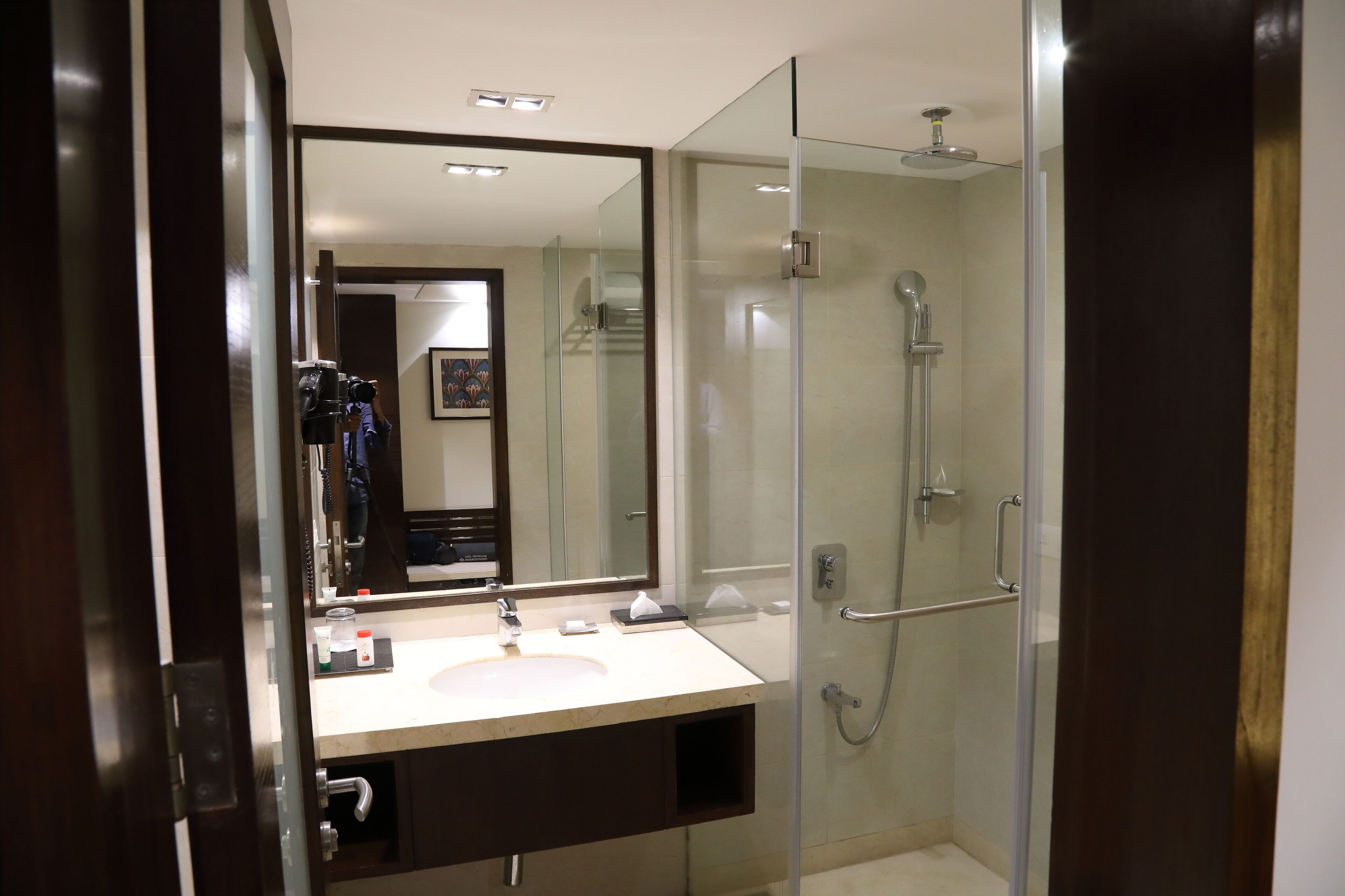 A modern bathroom with a glass-enclosed shower, a large mirror, and a dual sink vanity.