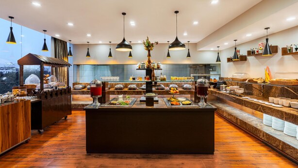 A modern breakfast buffet with a central island, overhead pendant lighting, and a view of the city.