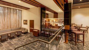 A bar area with seating, a staircase, and a view of the bar.