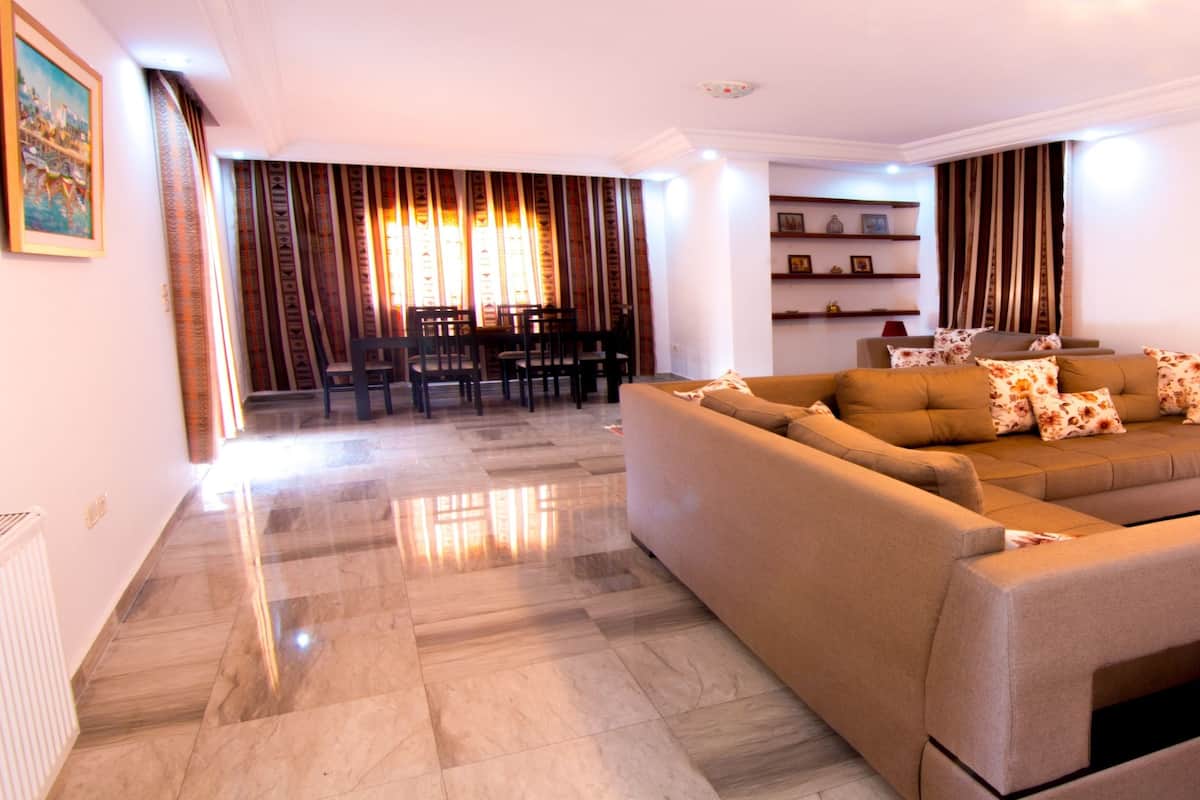 A modern living room with a sectional sofa, a coffee table, and a dining area with chairs and a table.