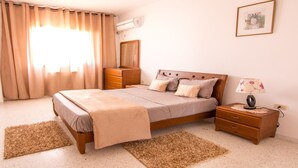 A bedroom with a bed, wooden nightstand, dresser, and a wall-mounted air conditioner. - Mahdia Place Apartments (Mahdia)
