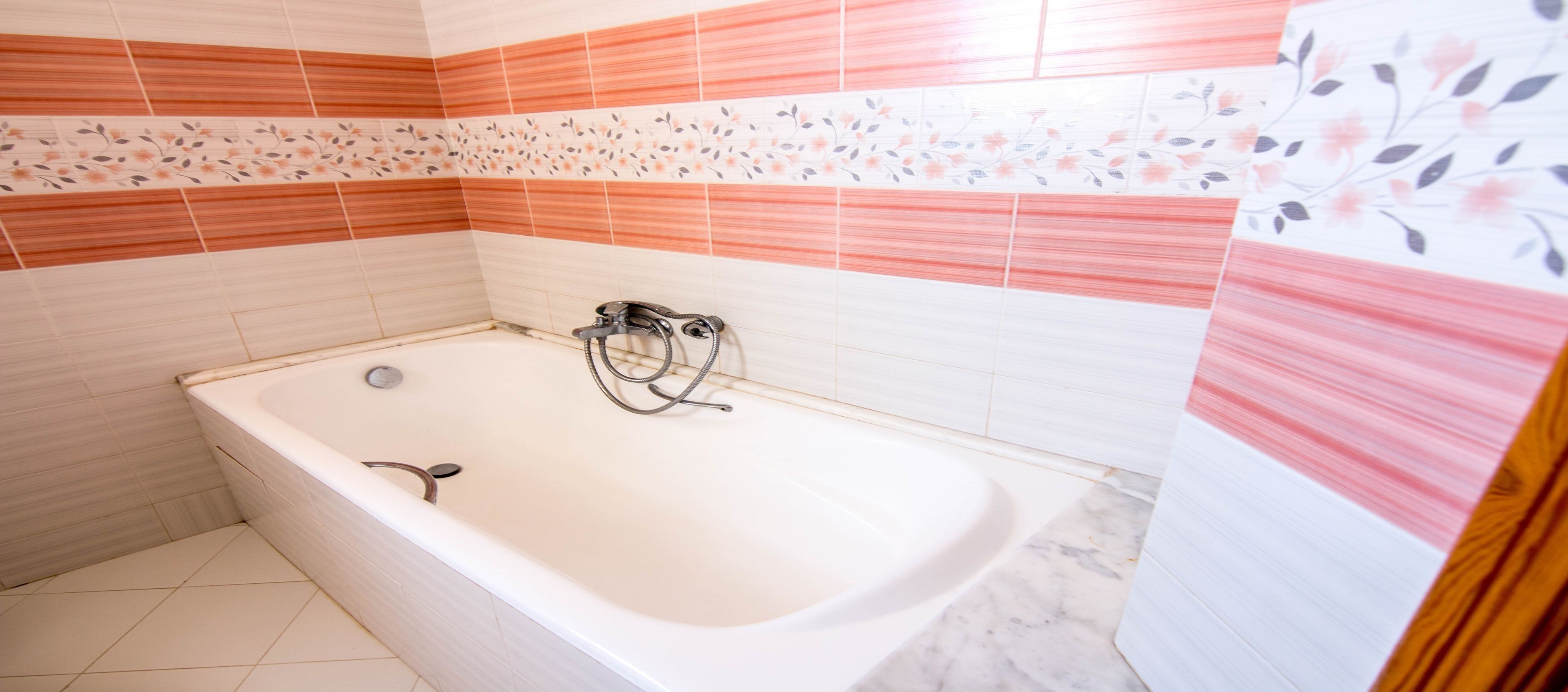 Une salle de bain avec une baignoire, des murs carrelés et un espace douche.