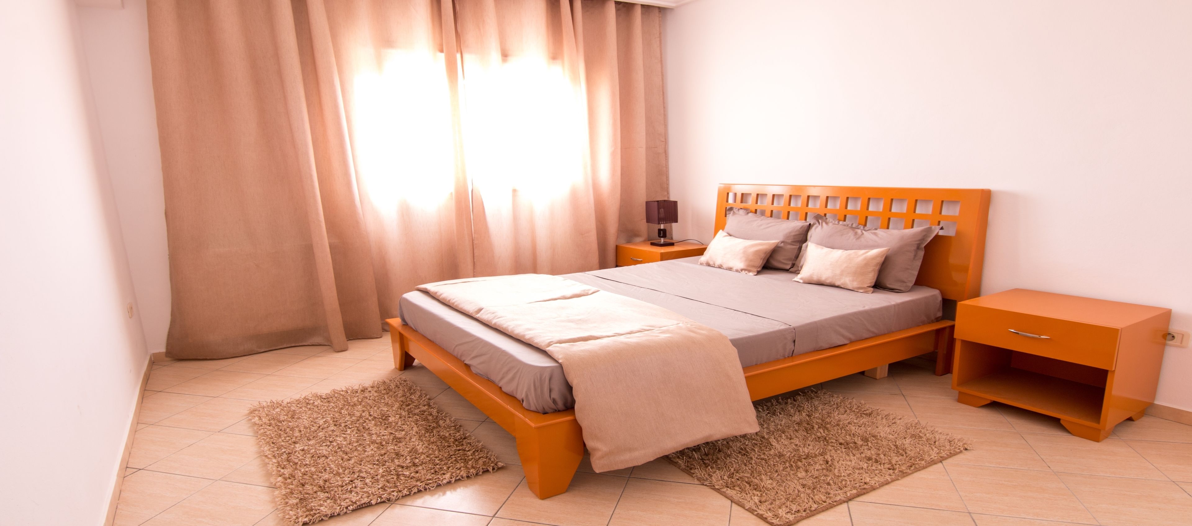 Une chambre à coucher avec un lit en bois, une table de chevet, une commode et un petit meuble.