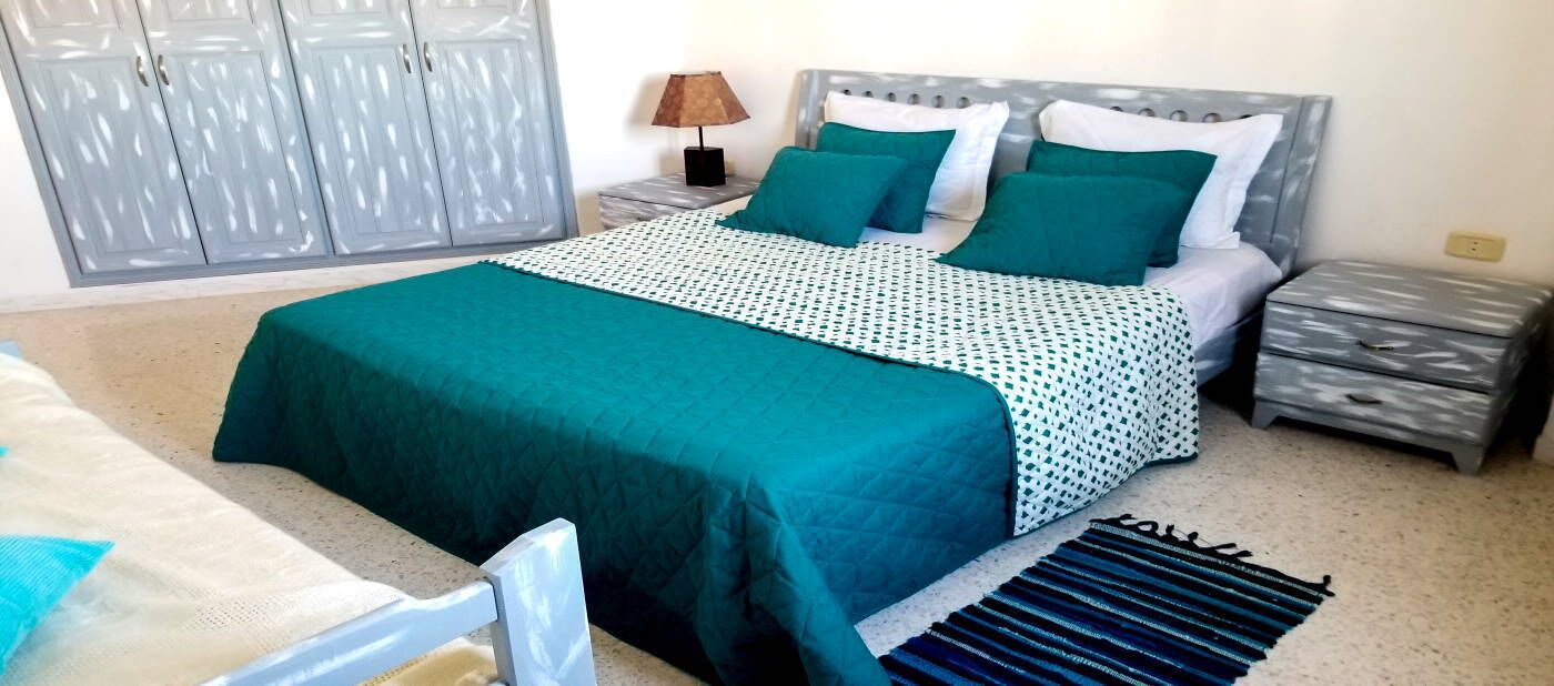 A bedroom with a bed, nightstands, a lamp, and a wardrobe.