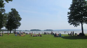 Un parque con césped donde la gente se relaja y algunos niños juegan.