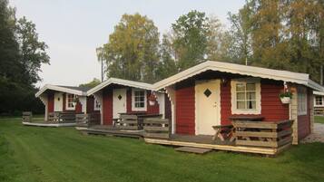 A row of red cabins with white trim, each featuring a porch and a picnic table.