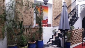 Un patio con plantas en macetas, una escalera y un mural en la pared.