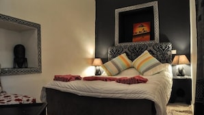 Un dormitorio con una cama, dos mesitas de noche, un espejo y un cuadro en la pared.