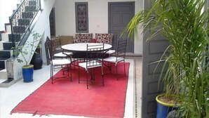 Un comedor con una mesa redonda y sillas, una alfombra roja y una escalera.