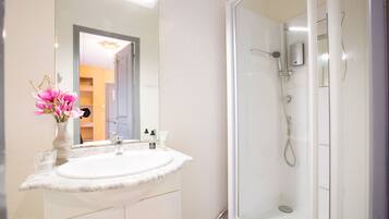A bathroom with a white sink, mirror, and shower.
