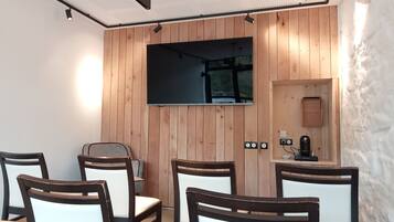 Een vergaderruimte met houten paneelwanden, een groot flatscreentelevisie en een kleine kitchenette.