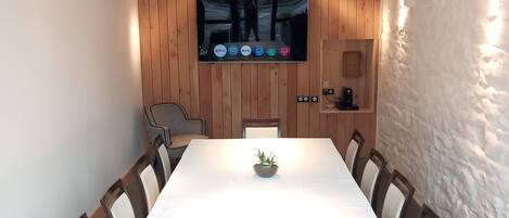 A conference room with a long table, wooden panel walls, a mounted TV, and a stone accent wall.