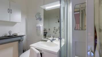 A modern bathroom with a white sink, a glass shower enclosure, and a toilet.
