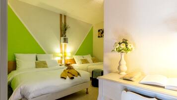 A hotel room with a bed, bedside table, lamp, and a vase with flowers.