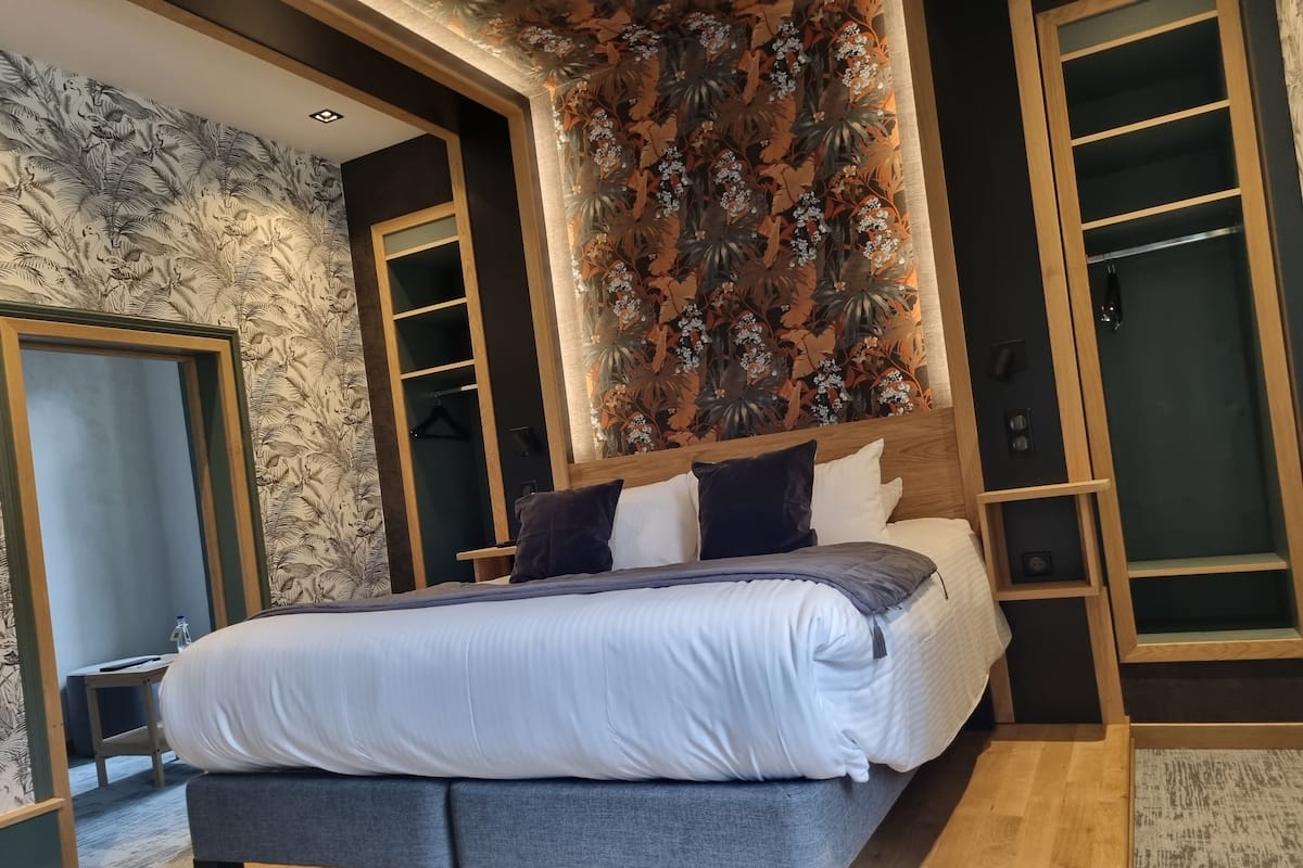 A modern bedroom with a large bed, built-in wardrobe, and a decorative wall panel.