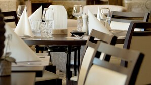 A dining area with marble walls, a table set with glasses, plates, and a lamp. - Hôtel de la Brasserie de Treignac (Treignac)