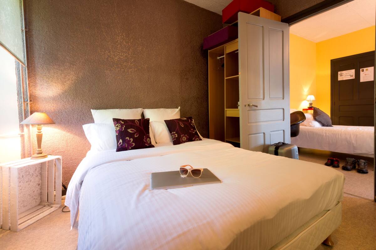 Ein Hotelzimmer mit einem Bett, einem Nachttisch mit Lampe, einem Kleiderschrank und einem Koffer.