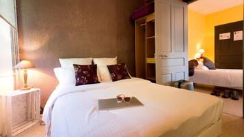 Une chambre d’hôtel avec un lit, une table de chevet avec une lampe, une armoire et une valise.