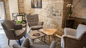 A cozy lounge area with stone walls, comfortable seating, and a fireplace. - Hôtel de la Brasserie de Treignac (Treignac)