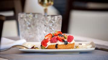 A dessert on a plate with a glass and a spoon in the background.