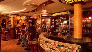 Un espace bar avec des tabourets, un comptoir et un panneau indiquant la section des cocktails.