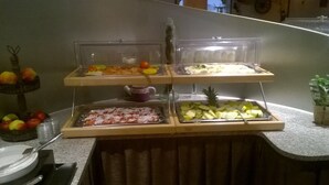 Un buffet avec différents plats présentés dans des récipients transparents.